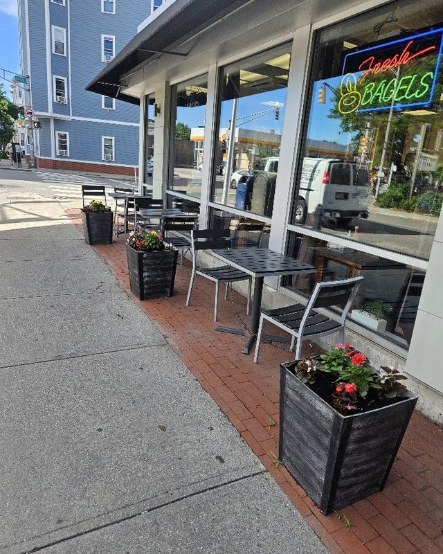 Planted containers along a storefront sidewalk cafe